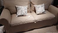 Two linen pillows on beige sofa, showing size and condition.