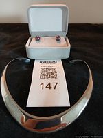 Sterling silver choker necklace with visible wear, laid flat with pearl stud earrings in original box behind it.