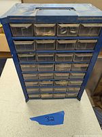 Front view of the blue plastic cabinet with 32 transparent drawers, showing overall condition and design.