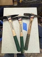 Photo showing all three mini gardening tools with wooden handles and black metal heads laid on a light-colored table.
