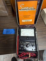 Simpson 260 volt-ohm-milliammeter in original case with operator's manual, showing the front dial and control panel with attached red and black test leads.