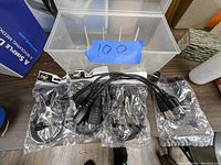 Plastic storage container holding various items including the disassembled fishing reel parts and hole saw base on a workbench.