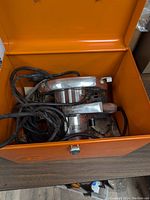 Top-down view of Craftsman circular saw inside orange metal carrying case showing power cords and saw body.