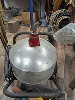 Top view of the galvanized metal drum housing with coiled cable and red collar from which the cable emerges.