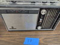 Front view showing metal speaker grill, brand name, frequency bands, and tuning knobs.