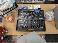 Open plastic case with 15 large drill bits arranged by size, showing spiral flutes