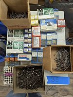 Top view of multiple boxes and containers of nails and brads with visible brand markings and labels.