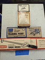 Photo showing three boxed tools on a white surface: a Craftsman dowel jig box, a Sears Craftsman trammel point box, and a Craftsman torque wrench box.