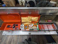 Wood planes, solder tubes, staples, pry bar, and open orange metal toolbox
