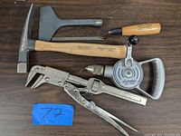 Full view of all tools on flat surface including hammer, chisel, pliers, manual drill, and small hook tool.