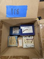Overhead photo showing multiple small boxes with various labels containing screws and fasteners inside a cardboard box.