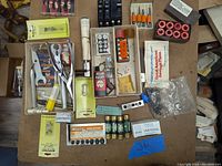 Top view of the lot showing all items on table including tools, fuses, relays, and packaging