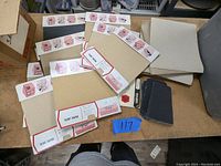 Multiple sandpaper sheets laid out on a table, some still in original packaging labeled 'Flint Paper'