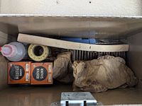 Metal storage case containing soldering supplies including Kester solder boxes, rosin flux, liquid flux bottle, wooden stick and paper-wrapped items.