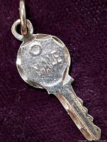 Close-up of the front side of the gold key pendant showing 'YALE' engraving and loop for chain bypass