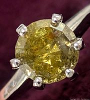 Close-up view of round brilliant cut yellow diamond showing color and faceting
