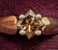 Close-up front view of ring band and princess-cut brown diamond showing setting and color
