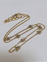 Photo showing gold-tone necklace with floral diamond accents laid out to display clasp and chain details.