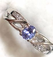 Close-up photo of the sterling silver ring showing the oval tanzanite gemstone and white topaz stones on the band.