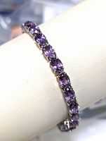 Close-up side view of the sterling silver amethyst bracelet showing the prong settings and purple oval-cut amethyst stones.