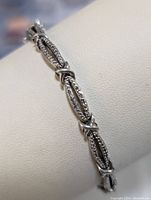 Close-up front view of sterling silver bracelet showing detailed oval links and X-shaped connectors.