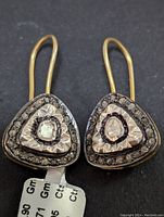 Top-down view of both triangular sterling silver earrings displayed side by side on black background, showing diamond settings in front face.