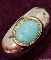 Close-up photo of sterling silver ring with oval aquamarine stone set in gold-tone bezel showing stone color and polished band.