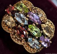 Close-up photo showing the multi-gemstone ring with various colored stones and silver setting