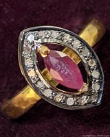 Close-up front angled view of sterling silver ring featuring marquise ruby center and diamond halo