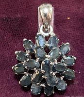 Close-up front view of the sterling silver sapphire pendant showing oval blue sapphires arranged in a tight cluster with a silver bail.