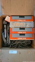 Box containing multiple ULM-105 and UDM-105 microphones with cables inside, some mics out of boxes, some boxes visible