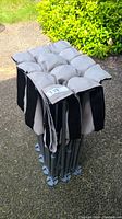 Folded camping cot showing tufted grey padded fabric and compact foldable frame.