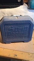 Closed blue molded plastic carrying case with Drill Doctor logo.