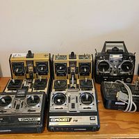 Overview image displaying all seven Futaba RC transmitters arranged on a table showing various models and designs from vintage analog to digital simulator controller.