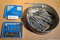 Overview of the three main components in the lot: metal tin with screwdrivers, blue case of bits and handle, blue case of precision tools