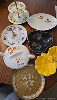 Full view of all ceramic servers and bowls including two-tier stand, single-tier plate, divided bowl, and yellow flower-shaped bowl.