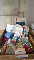 Lot showing sewing rulers, tools, pins, and various sewing notions displayed together in a box