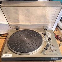 Top-down photo showing the turntable platter, tone arm, and control knobs with dust cover open.