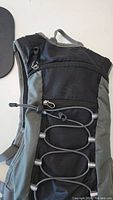 Front view of a black and gray backpack with bungee cord and zipper pocket