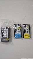 Three sealed HP ink cartridges laid flat on a surface: Black 950XL, Cyan 951XL, and Yellow 952XL.