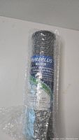 Photo of a black cylindrical PurePlus CTO10 activated carbon block water filter wrapped in bubble wrap showing the product label and brand.