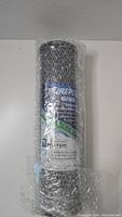 Photo of PurePlus CTO10 carbon block water filter wrapped in bubble wrap, showing label and size specifications