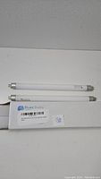 Two Bluex Bulbs F6T5/CW 6 watt fluorescent cool white light bulbs and one box labeled Bluex Bulbs on a white surface.