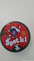 Closed round tin container of Spot It game showing holiday-themed lid design