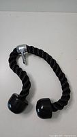 Photo showing black twisted tricep rope with plastic grip ends and metal clip for attachment.