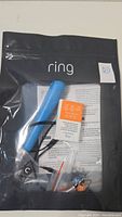 Black resealable bag labeled 'ring' containing the P4o Power Kit V3 items including a blue cylindrical battery, instruction sheet, small screws and components.