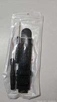 Photo of a black silicone watch strap and two small screwdrivers packaged in a sealed clear plastic bag.