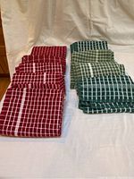 Set of 9 microfiber checked dish towels, 5 red and 4 green, laid flat to show color and checkered pattern.