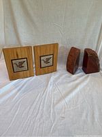 Close view of the wood, metal, and ceramic Canada Goose bookends paired with red agate geode bookends on a white cloth.