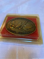 Close-up of the front of the brass belt buckle showing embossed company name and images of pan, pick, and shovel.